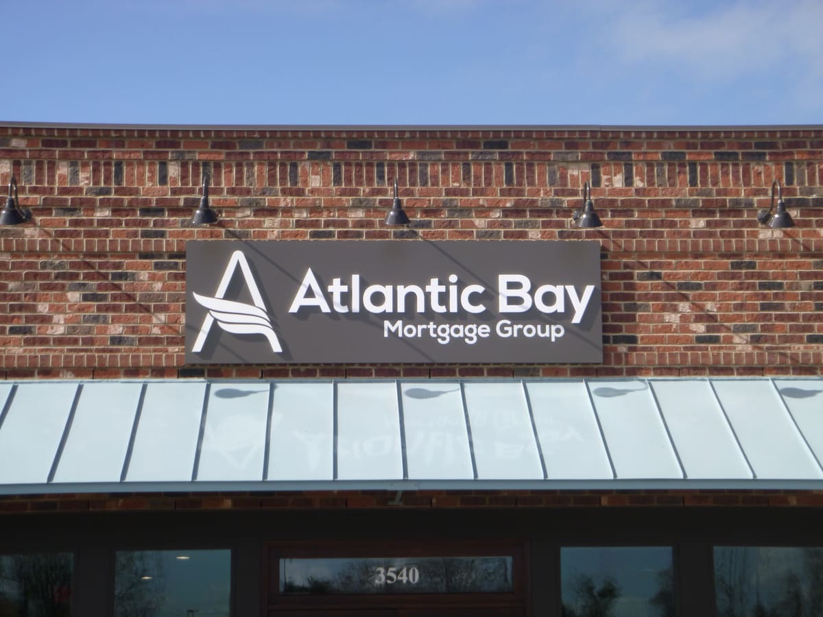 Atlantic Bay Mortgage Group panel sign with gooseneck lights on a brick facade