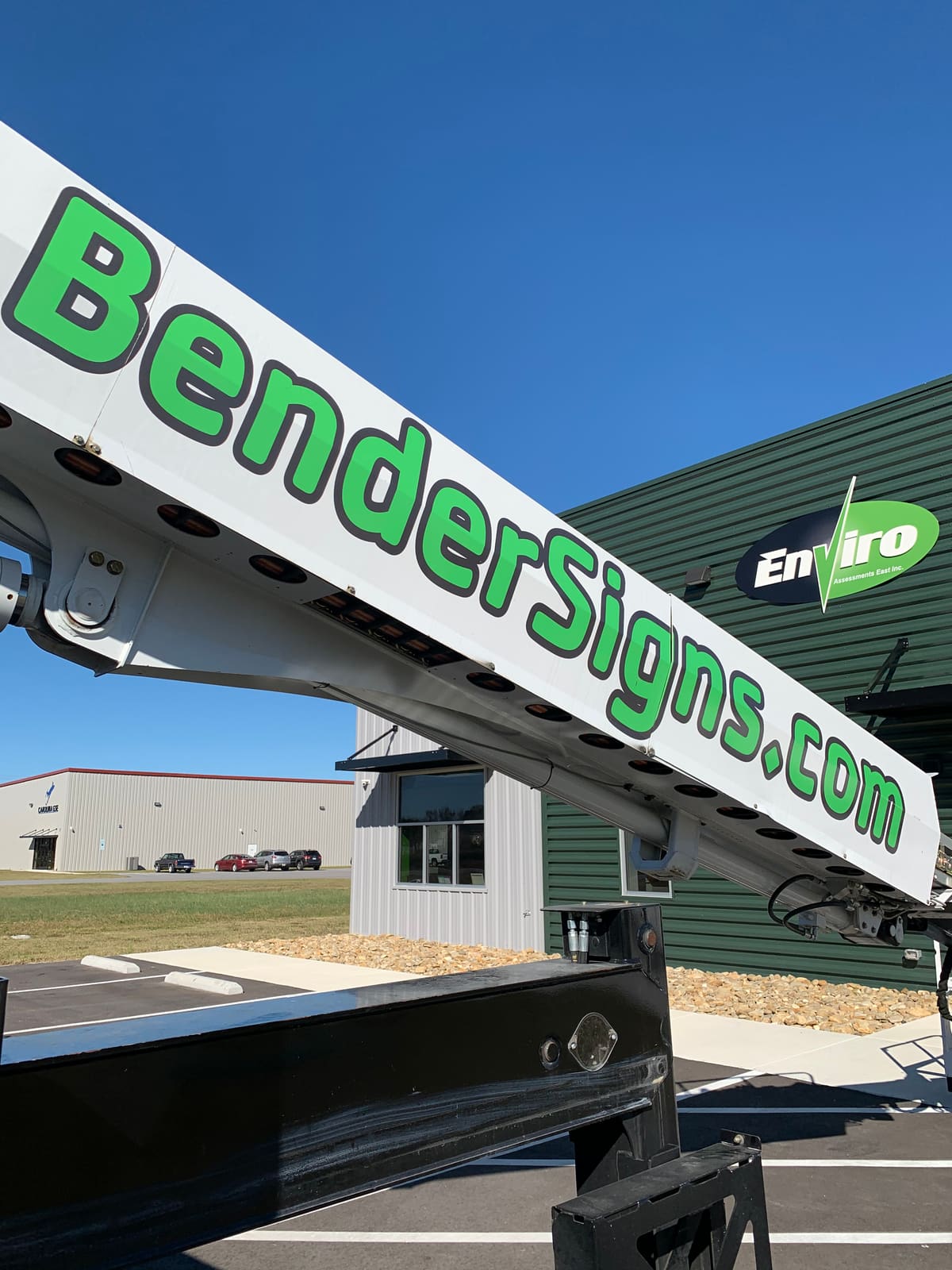 BenderSigns.com crane boom extended against a clear blue sky on a job site