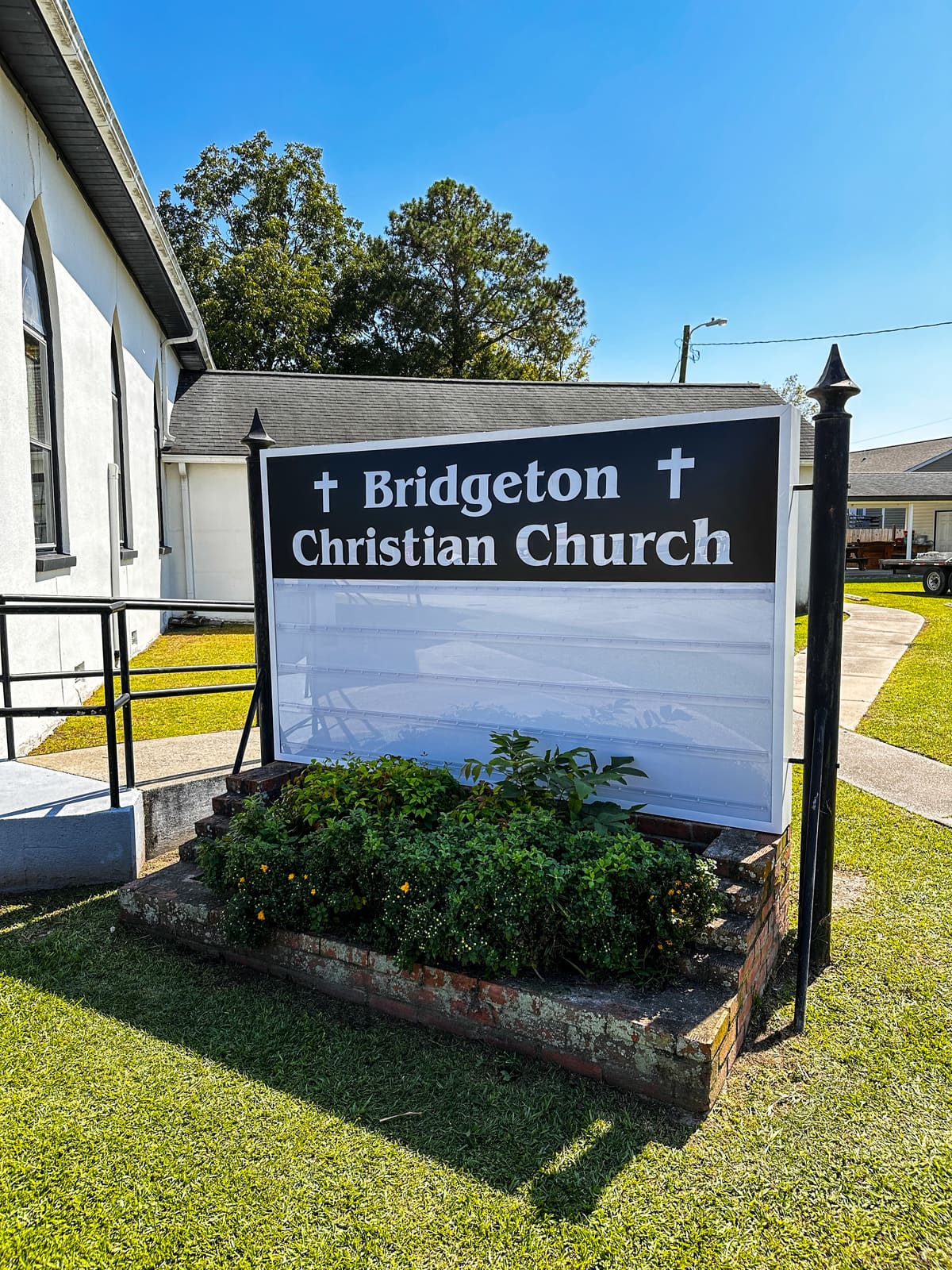 Bridgeton Christian Church marquee sign in a brick planter beside the white church