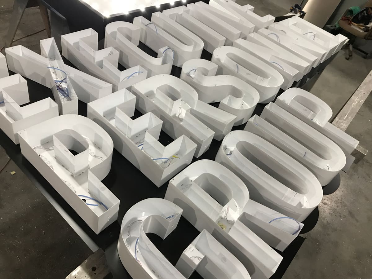 Channel letter cans with exposed LED modules and wiring on the fabrication table