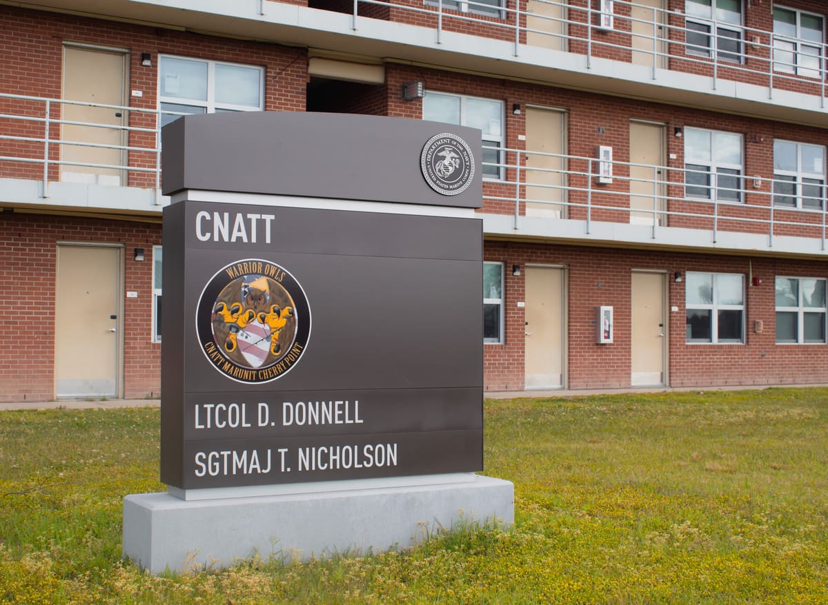 CNATT barracks monument sign with unit crest in front of brick barracks at Cherry Point