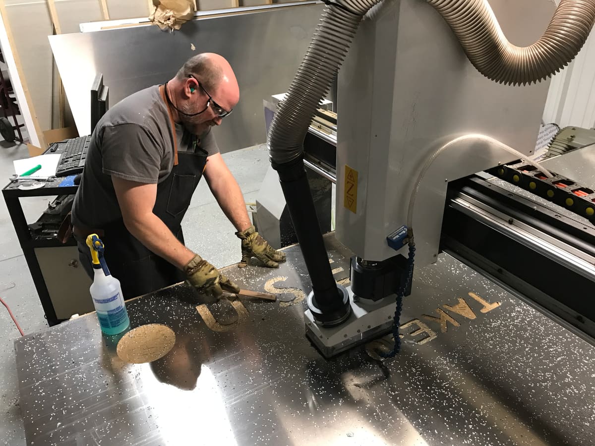 Fabricator brushing chips off CNC-routed aluminum letters on the router table