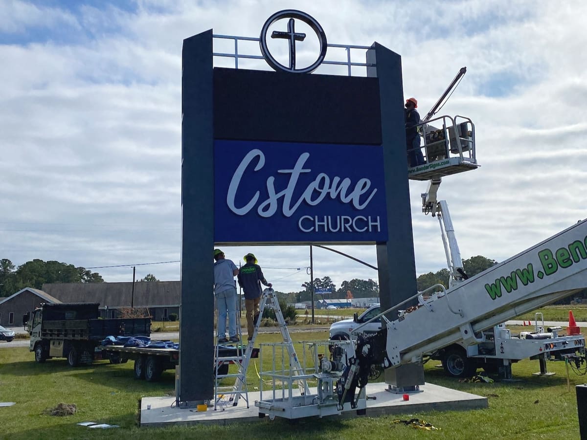 Crew installing the C Stone Church LED pylon sign with Bender bucket truck and ladders