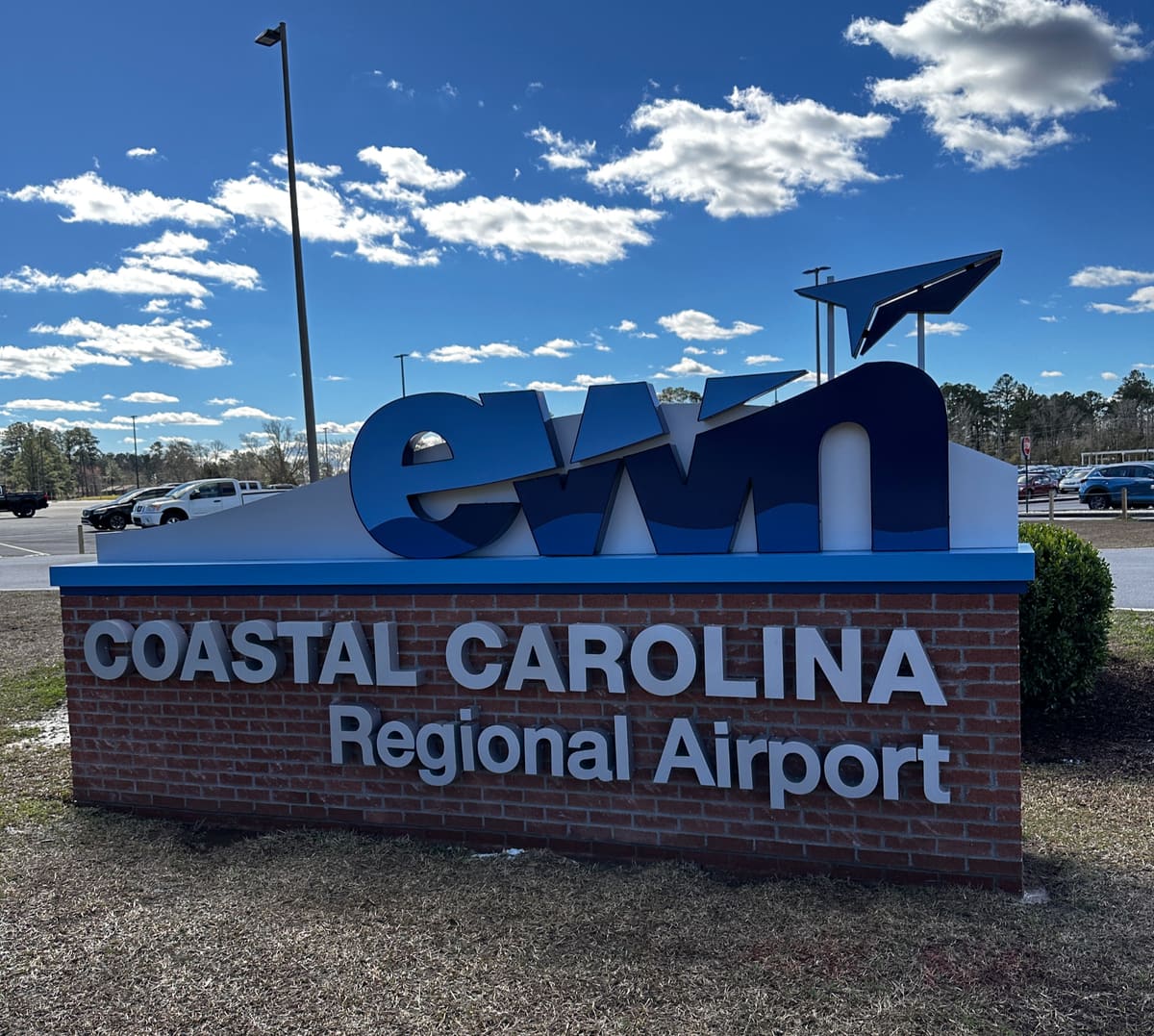Coastal Carolina Regional Airport brick monument sign with lowercase ewn letters under a blue sky