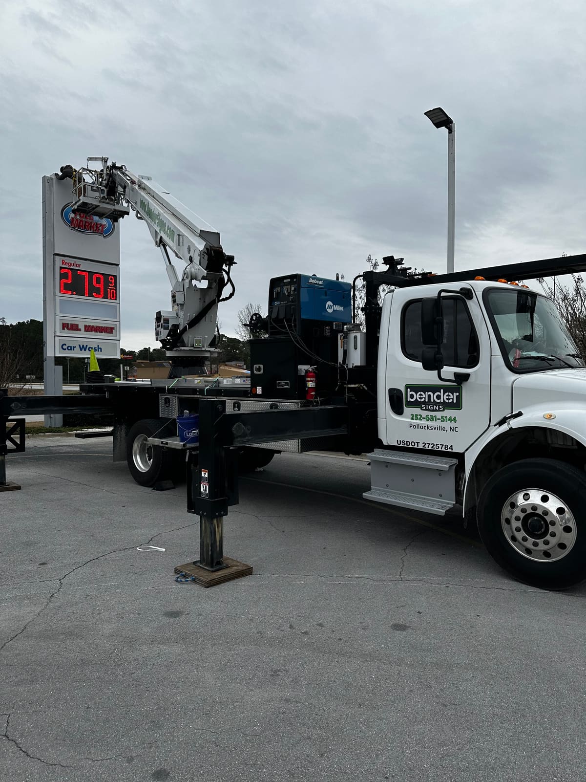 Bender Freightliner crane truck servicing a Fuel Market LED price sign