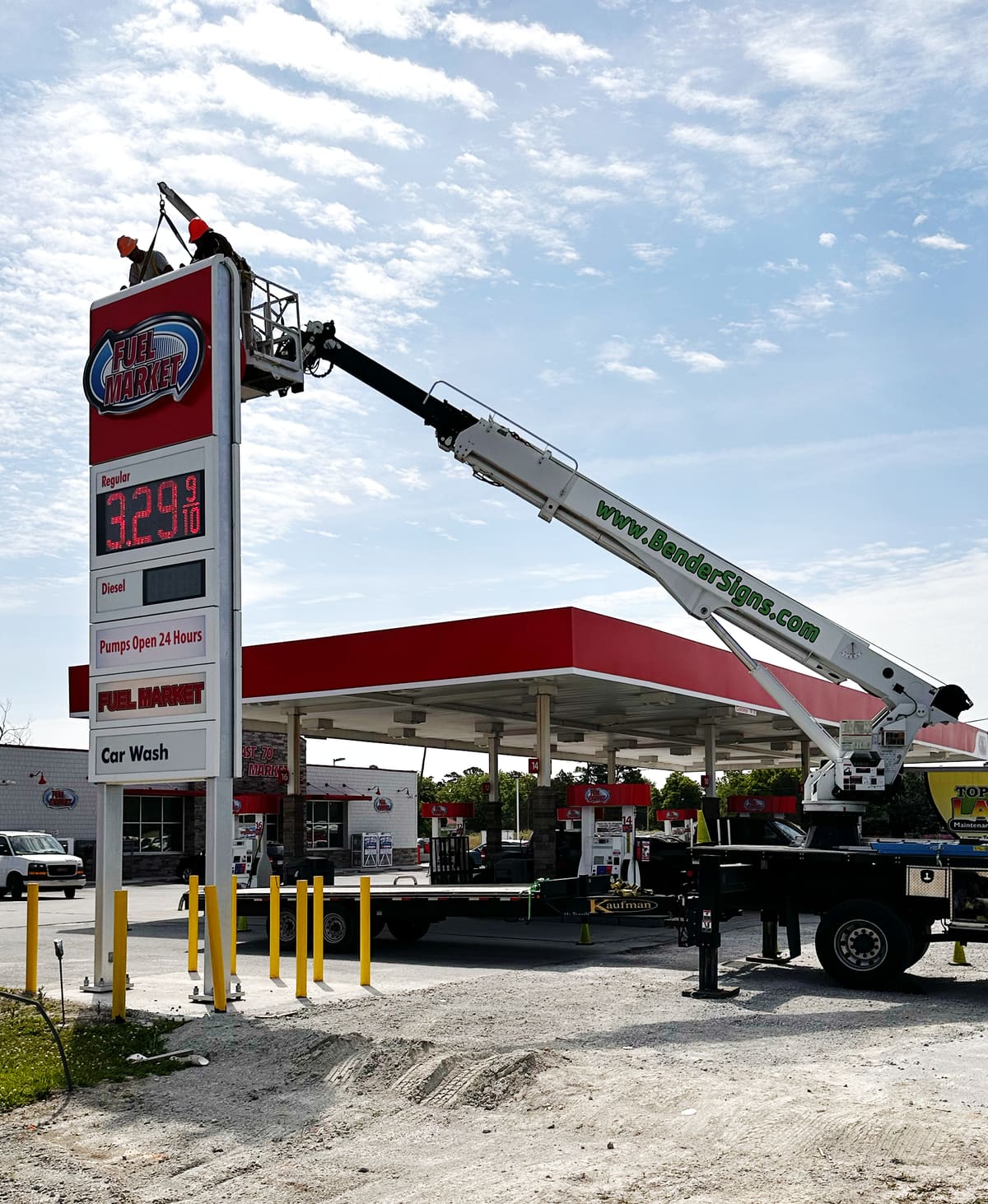Crew atop the Fuel Market gas-station pylon with the Bender crane arm across the frame