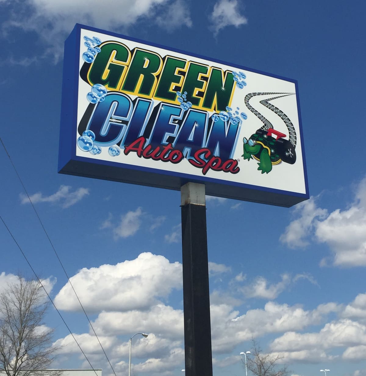 Green Clean Auto Spa double-sided pole sign cabinet against cumulus clouds