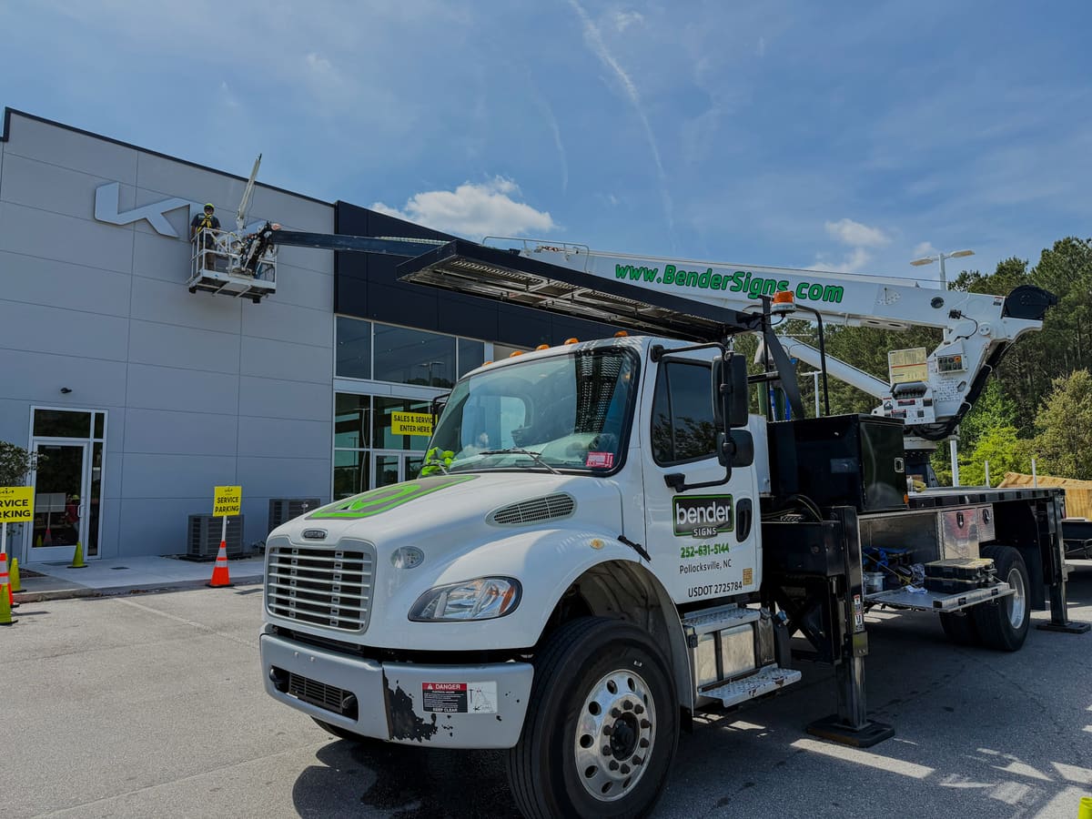 Bender Signs Freightliner crane truck with crew in the lift servicing a Kia dealership sign