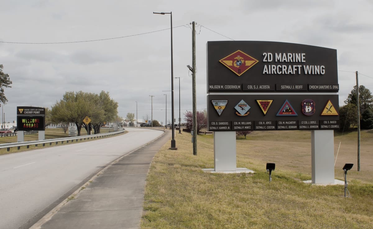 2D Marine Aircraft Wing command board with unit insignia along a base road at Cherry Point