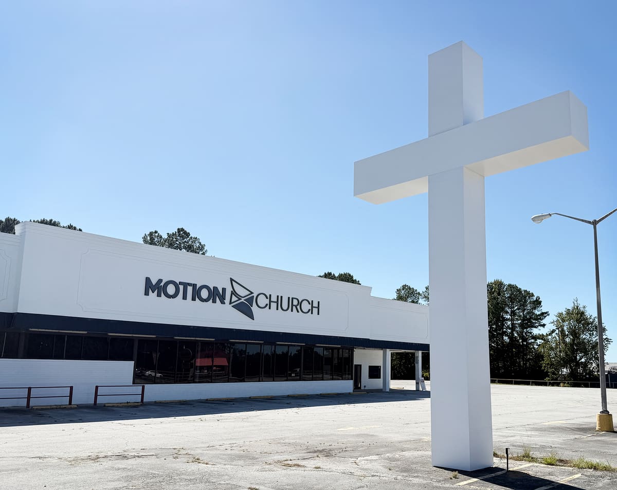 Motion Church building letters beside a giant white pole-mounted cross