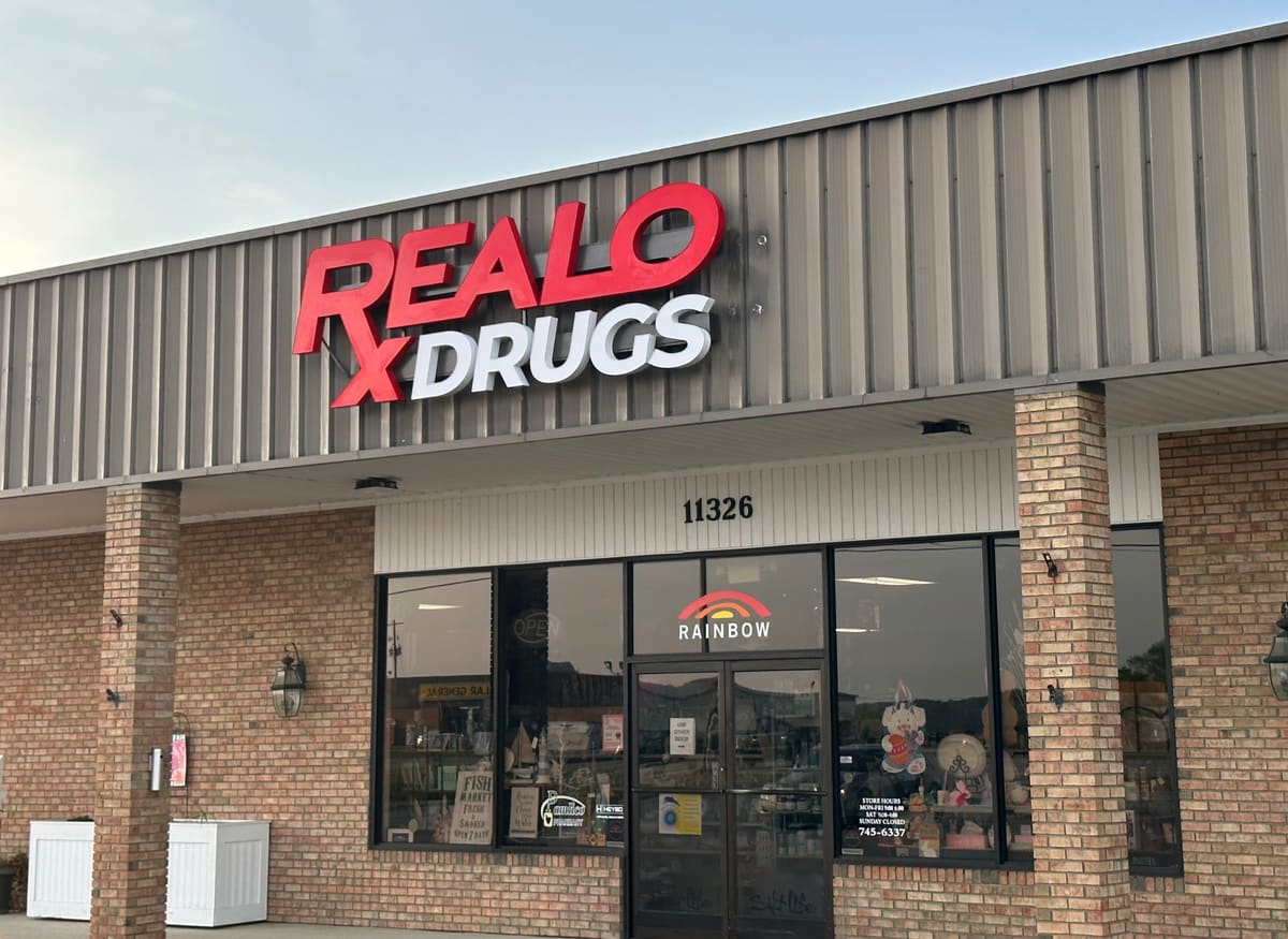Realo Drugs channel letters on a brick storefront at dusk