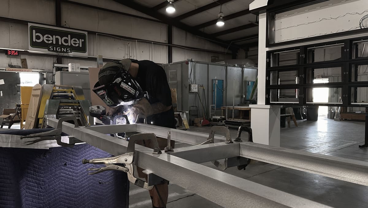 Welder fabricating an aluminum sign frame on the Bender Signs shop floor