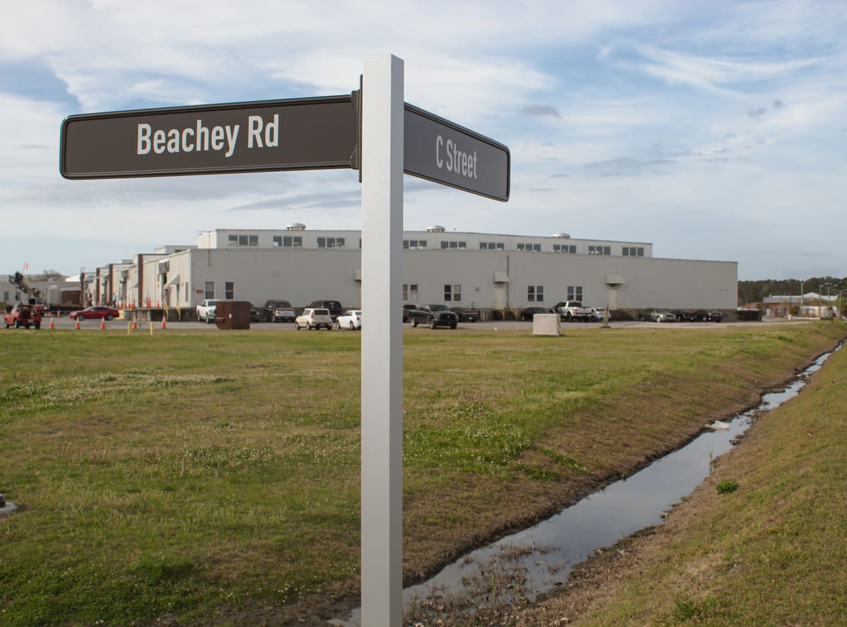 Custom street-name blade signs on an aluminum post at the base