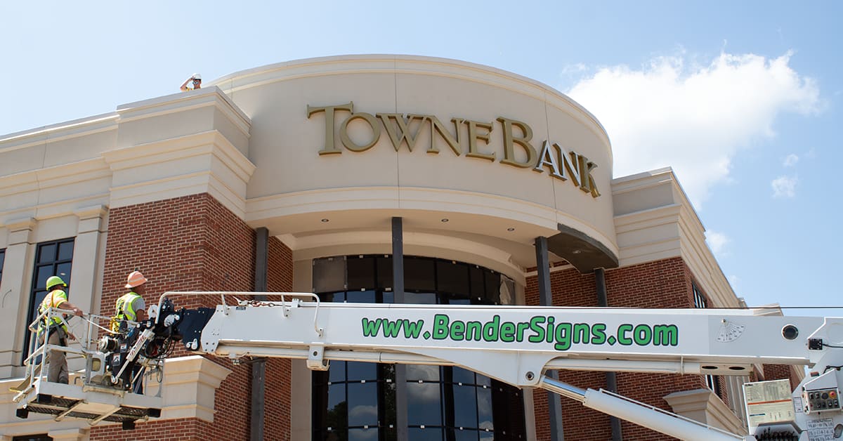 Two crew in the BenderSigns.com bucket crane installing TowneBank letters on a curved facade
