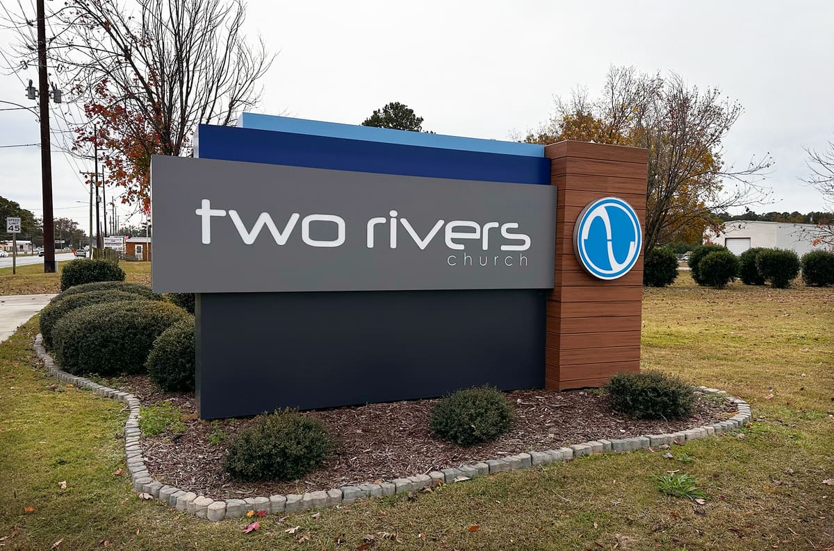 Two Rivers Church modern monument sign with wood-look column and round logo