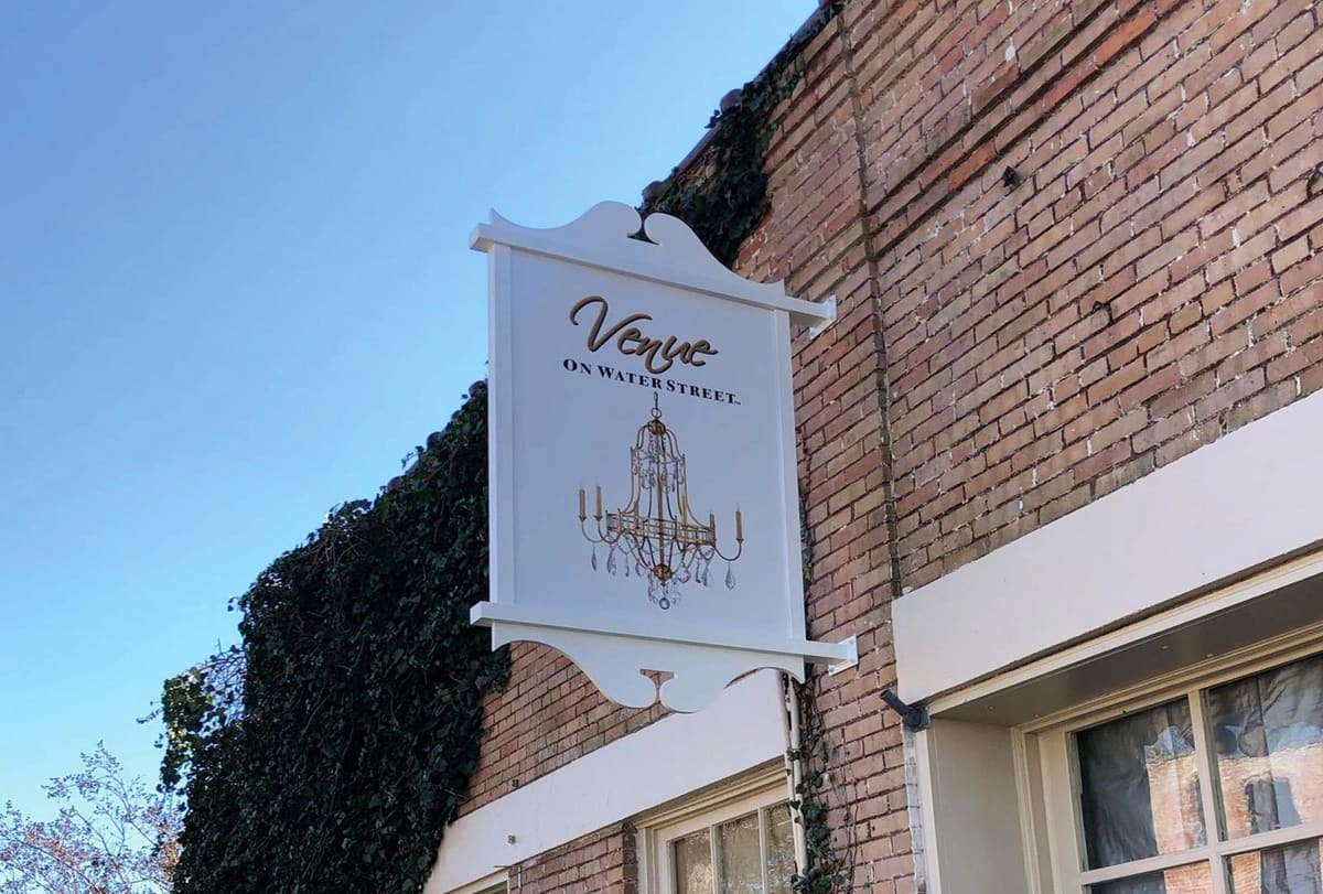 Venue on Water Street white blade sign with chandelier graphic projecting from the facade