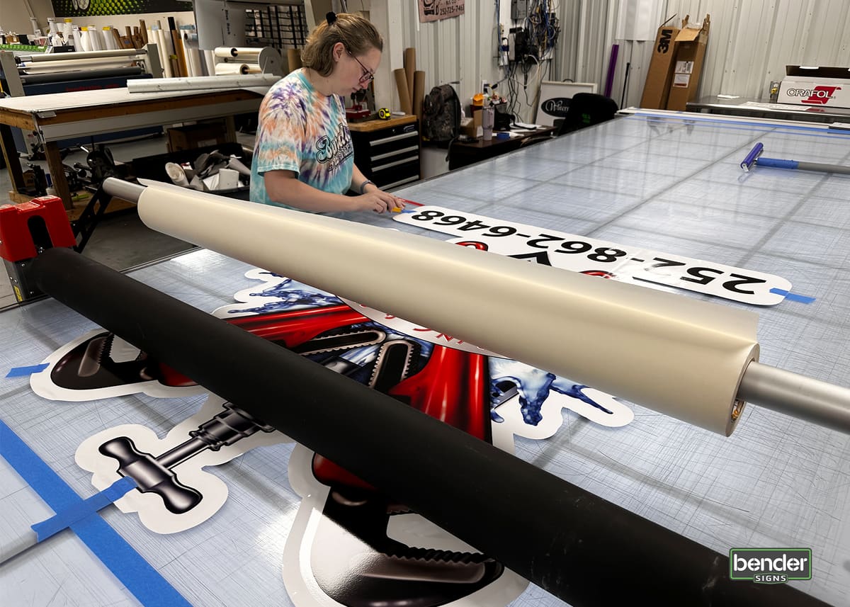 Employee weeding printed vinyl decals on the print-shop worktable